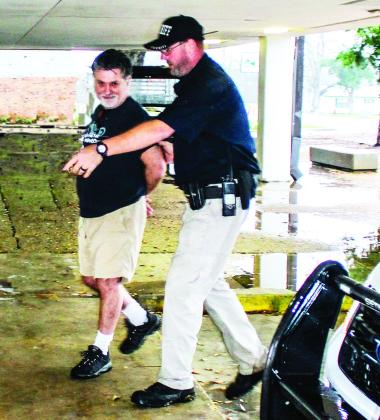 Myles McMillin being escorted into the Catahoula Parish Jail by Officer Chad Littleton for booking.